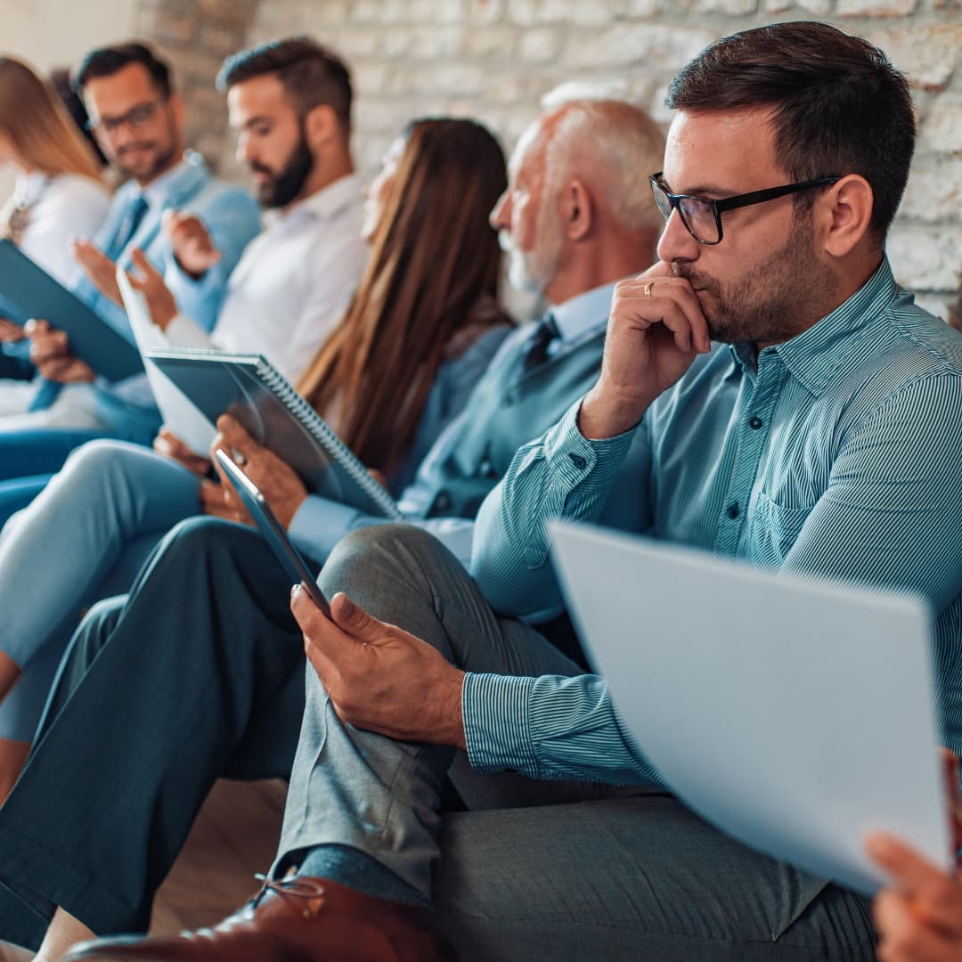 Personas revisando su CV u hoja de vida, esperan para hacer entrevista de trabajo